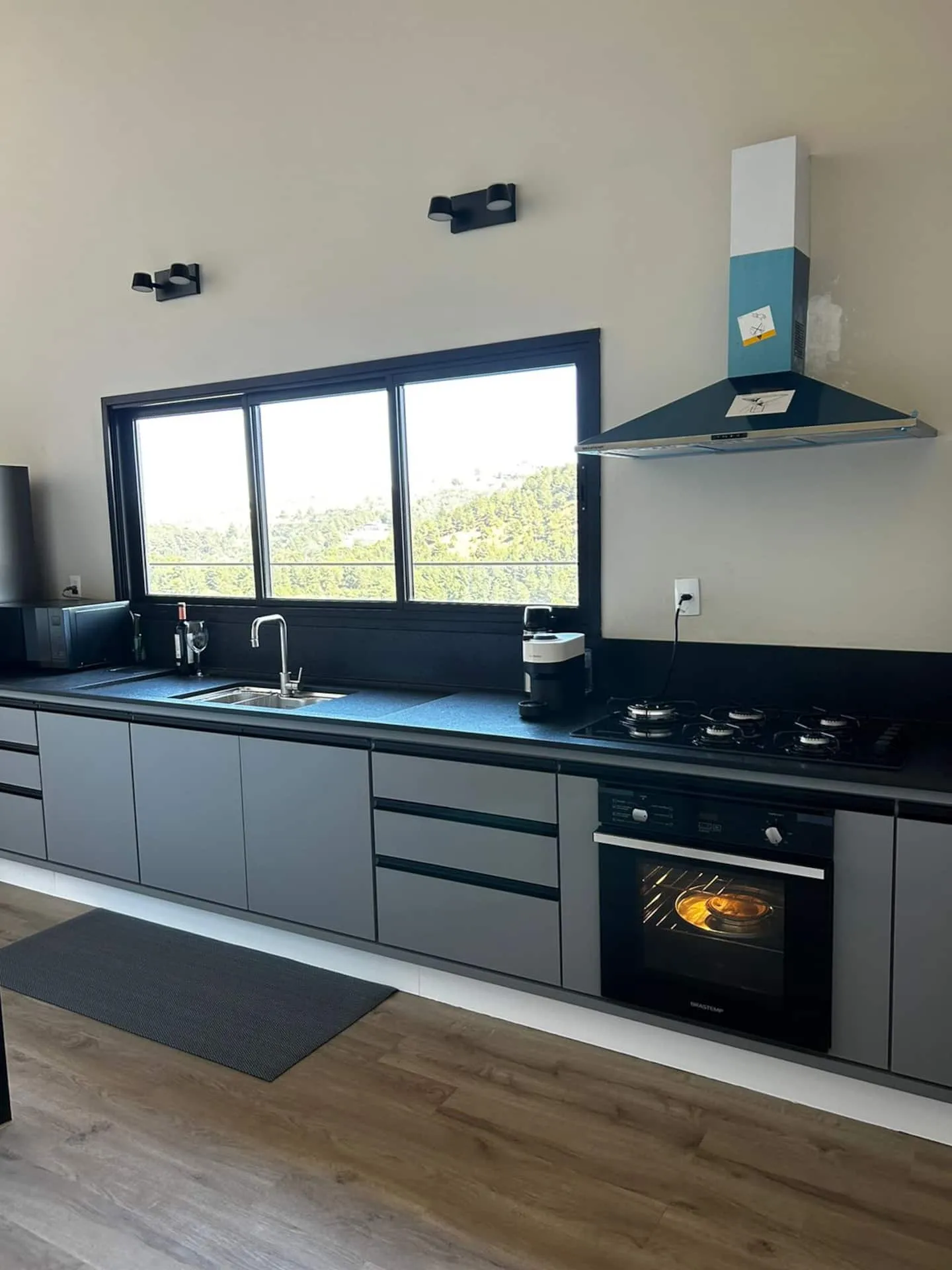 Cozinha com bancada escura, cooktop e forno embutido