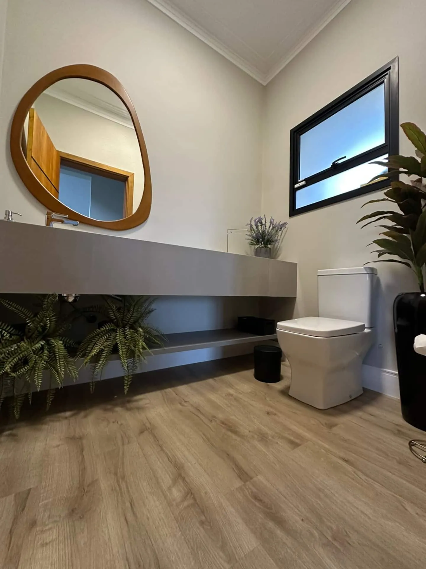 Lavabo de uso comum com espelho redondo emoldurado em madeira