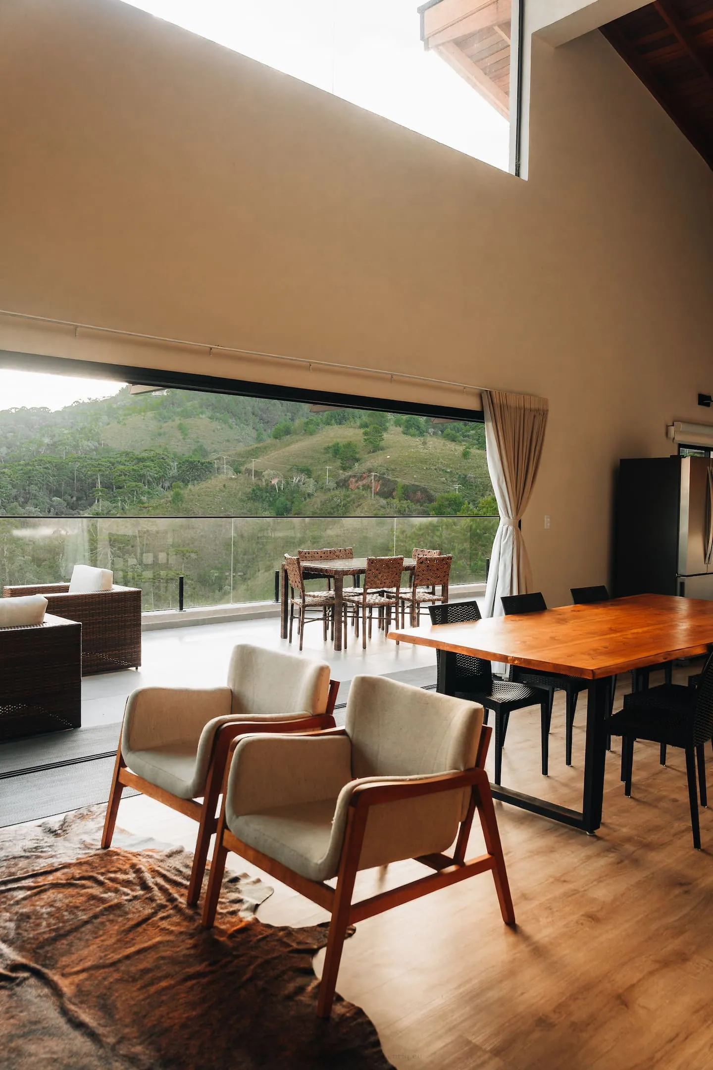 Poltronas claras e mesa de jantar diante da janela para as montanhas