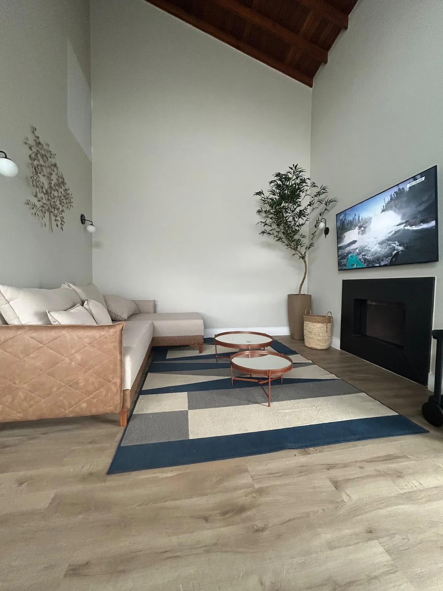 Sala de estar com sofá claro, lareira e TV sob o pé-direito alto