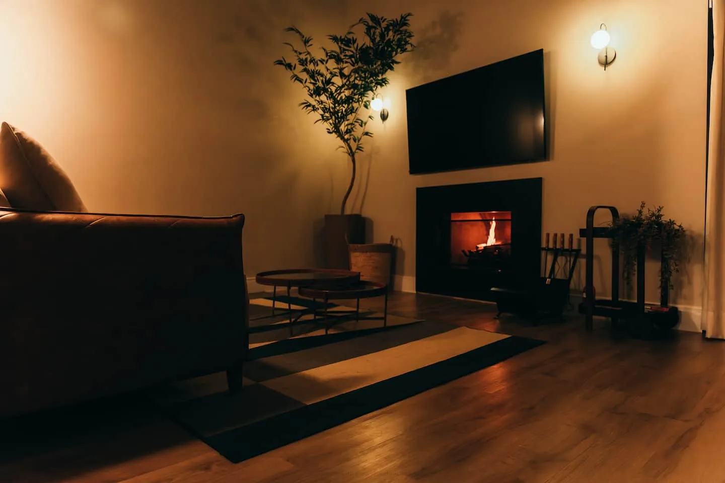 Lareira acesa na sala, com luz quente e poltrona de couro