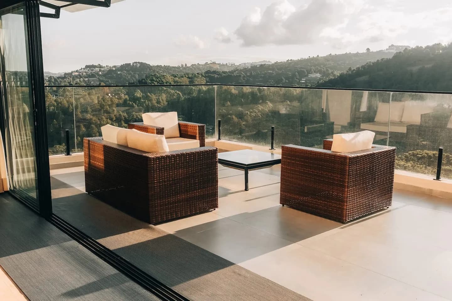 Poltronas na varanda atrás do guarda-corpo de vidro, com a serra ao fundo